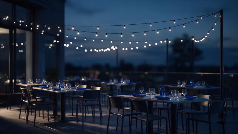 Terraza vacía al anochecer con mesas puestas y guirnaldas de luces, lista para un evento social