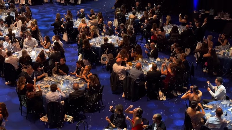 Asistentes de la VI Nit Bufona soplando pompas de jabón en las mesas del Palau de Fires, vistos desde arriba